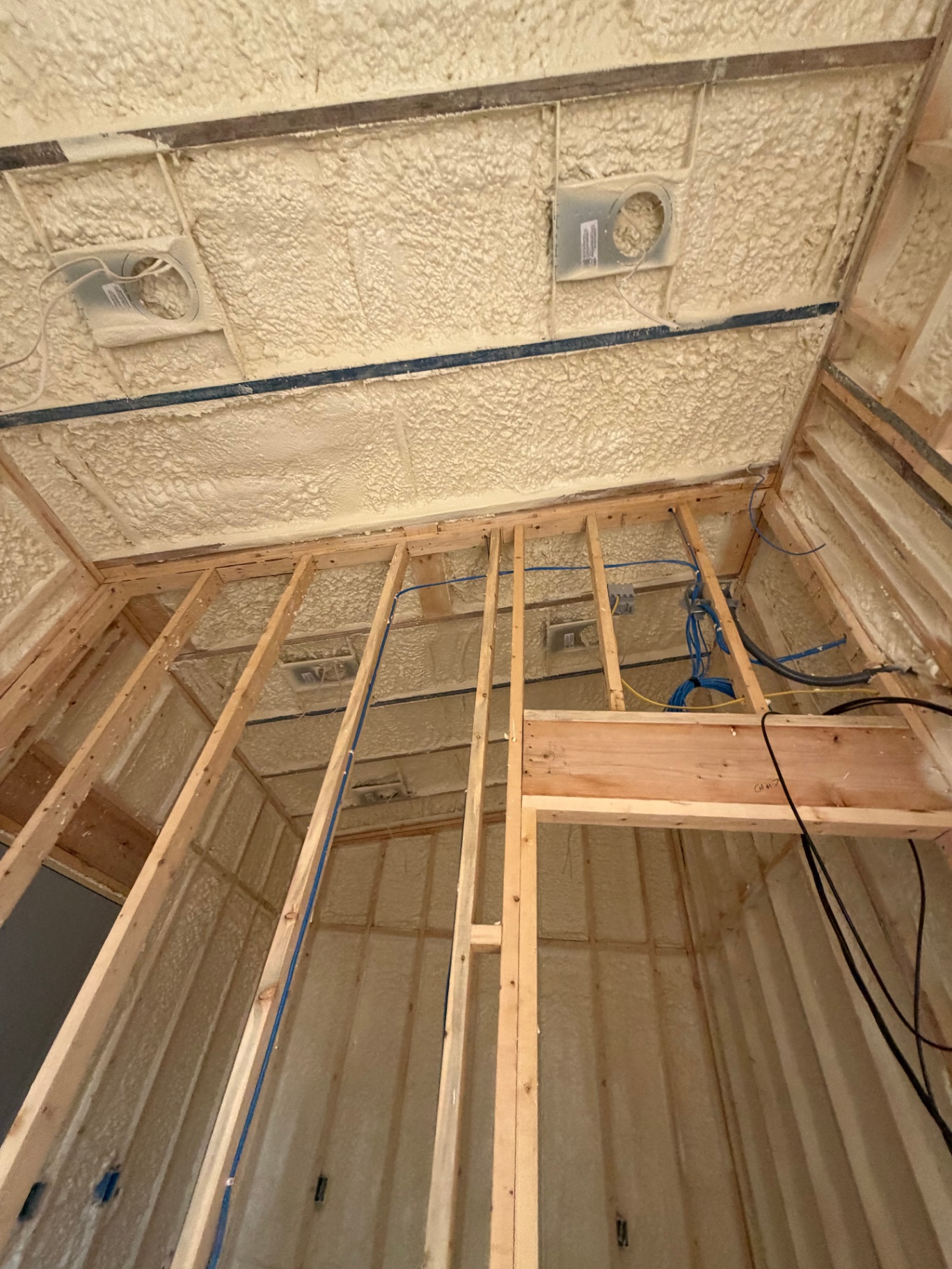 Spray foam insulation applied to wall cavities and ceiling in a residential addition