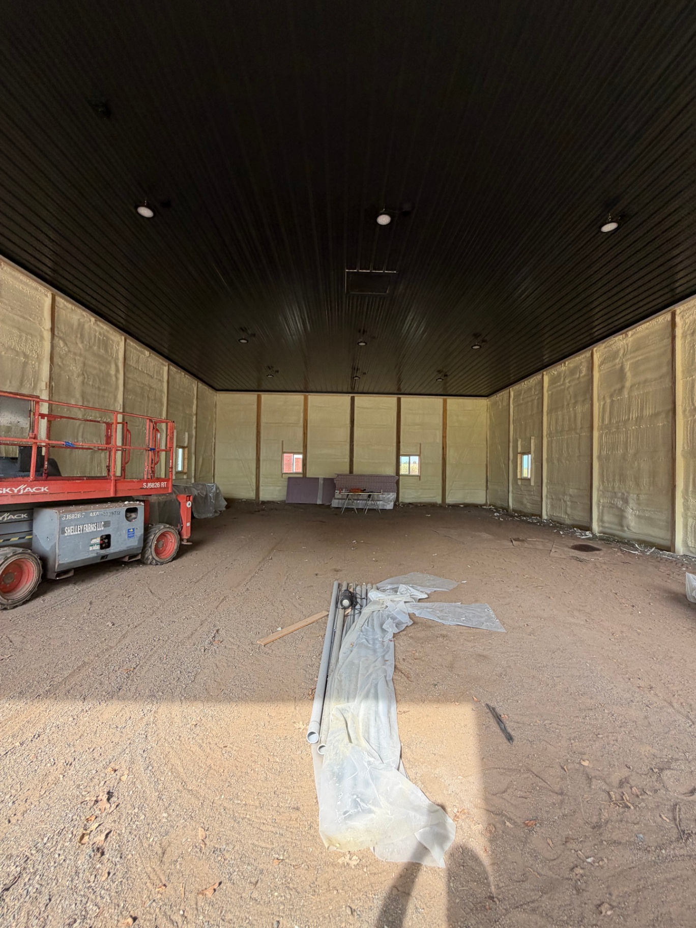 Commercial spray foam insulation in a pole barn shop with metal ceiling