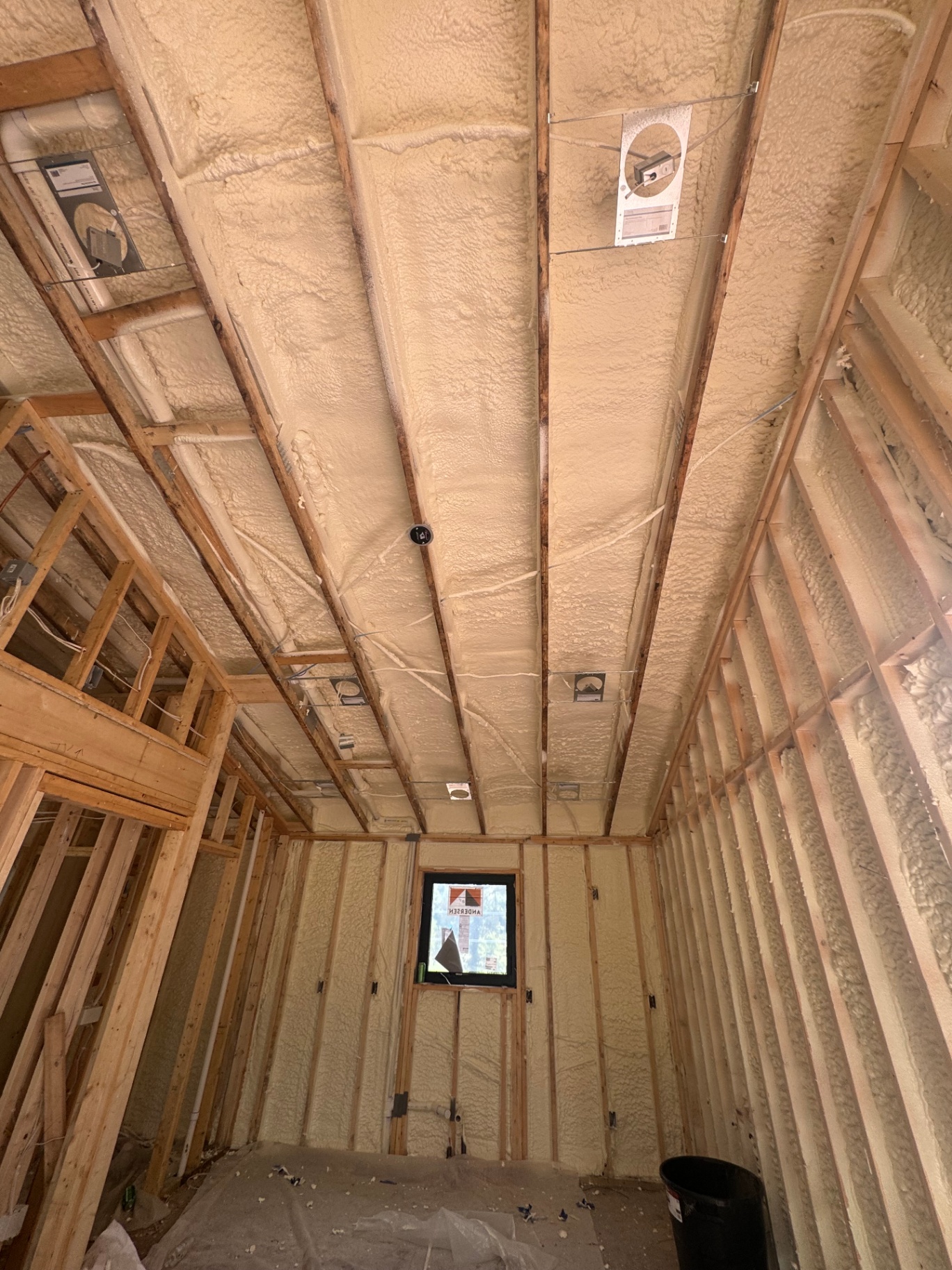 Closed-cell spray foam insulation sealing ceiling cavities in a new construction home